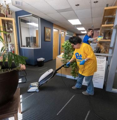 day of caring volunteer vacuuming a floor at Peoples Oakland