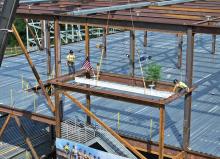 construction workers add a signed white beam to the bioforge structure